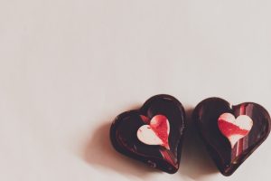 Top view of delicious heart shaped chocolate candies placed on white table in kitchen