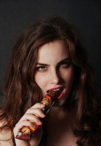woman biting on chocolate bar