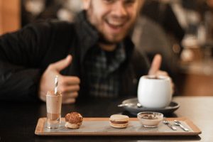 selective focus photography of smiling man in front of tray with pastries