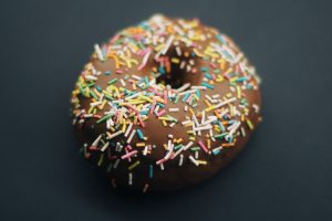 a chocolate donut with sprinkles on a black surface