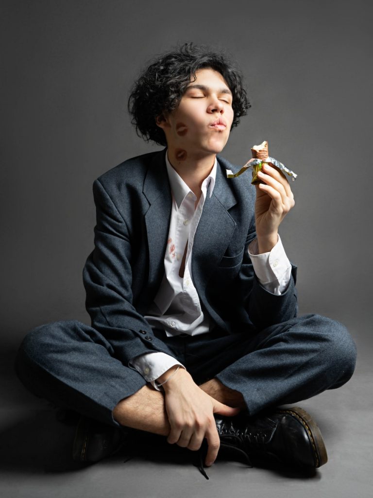 a man in a suit sitting on the floor with a cigarette in his mouth
