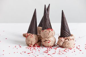 three cones of ice cream with sprinkles on a white surface